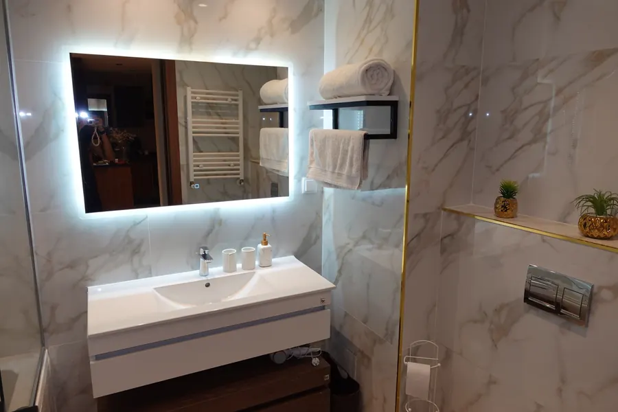 Backlit mirror over the vanity with towels on the shelf
