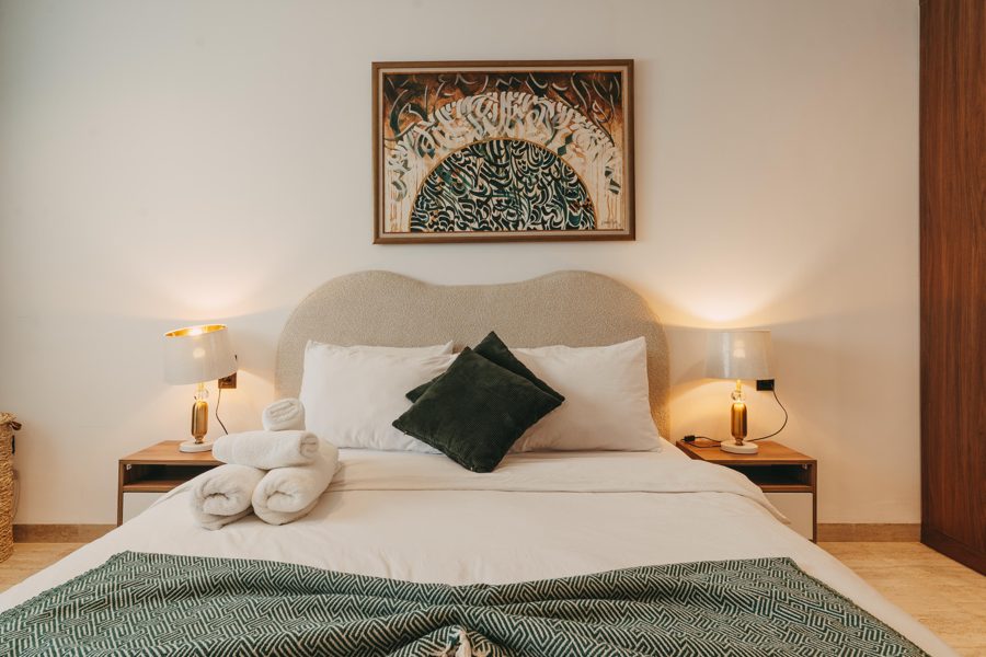 Bedroom with king bed, Tunisian calligraphy artwork and warm lighting