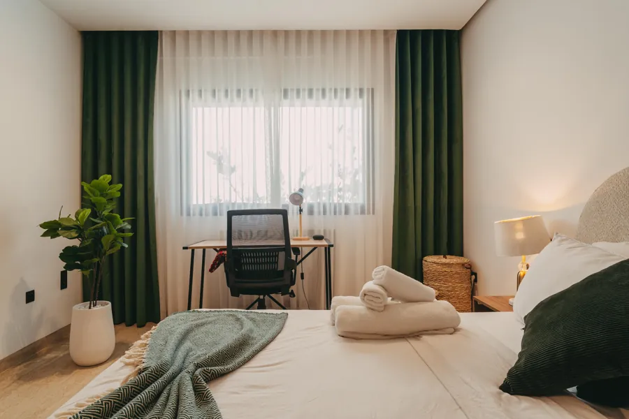 Bedroom desk corner with plant and green curtains