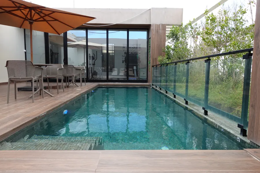 Rooftop pool with glass railing, parasols and seating